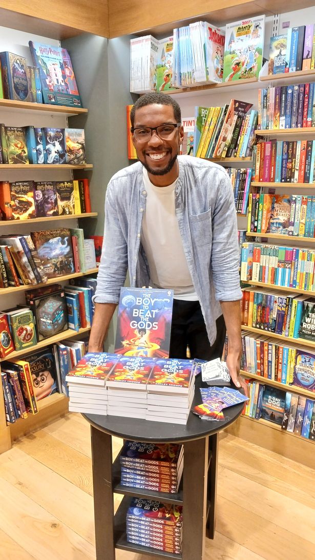 Ashley Thorpe poses for a picture in front of a his book