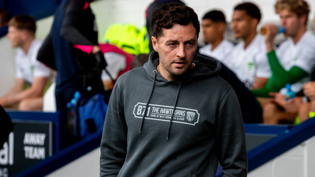 West Brom manager Ryan Mason stands on the touchline with a concerned expression on his face.