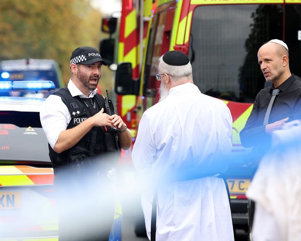 Police speak to members of the Jewish community at the scene