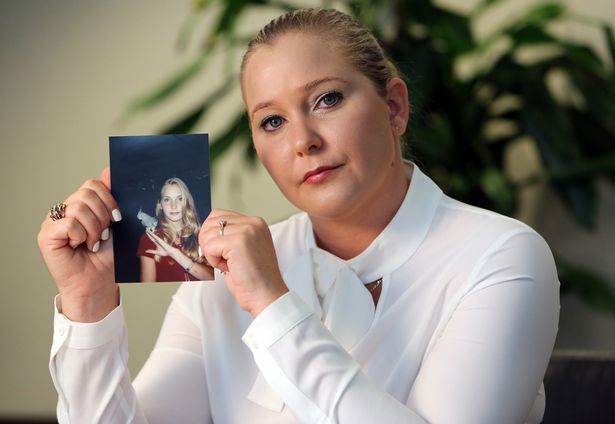 Virginia Giuffre holding an image of herself at age 16