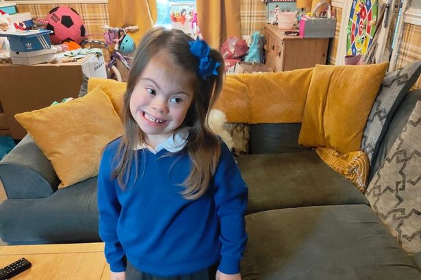 A sweet, smiling young girl in school uniform stood in a living room