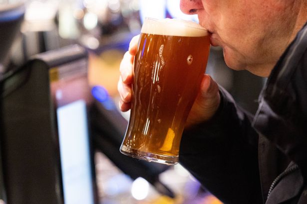 A customer drinks a pint of ale at the bar 