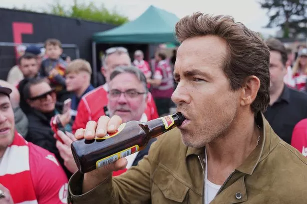 Ryan Reynolds sips a beer prior to the League One clash between Wrexham and Charlton Athletic at the Racecourse