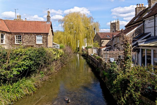 Pretty cottages and the Mells River at Nunney. Village of Nunney, Somerset, England, United Kingdom - 8th of April 2023