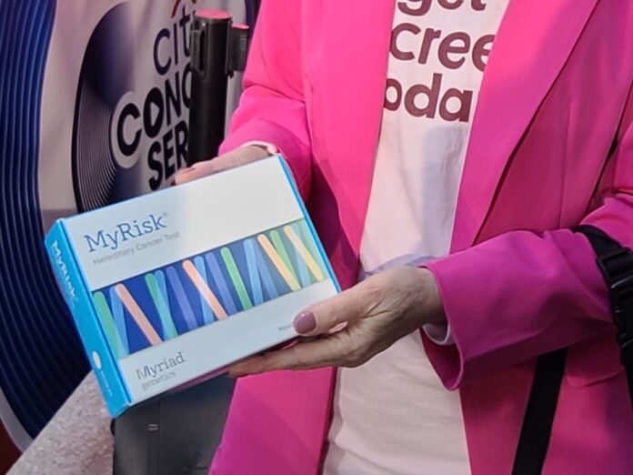MyRisk genetic screening kit being held by a person wearing a pink jacket