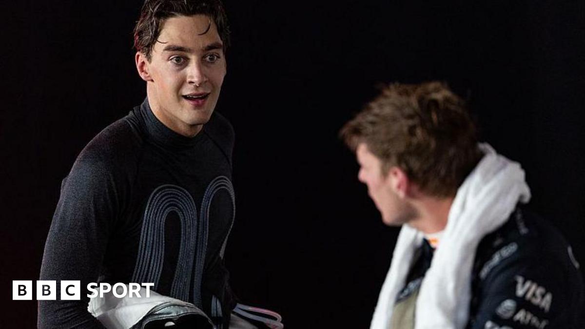 George Russell speaking to Max Verstappen after winning the 2025 Singapore Grand Prix, with his race suit pulled down and his cooling vest visible