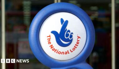 A photograph of the National Lottery logo displayed outside a shop