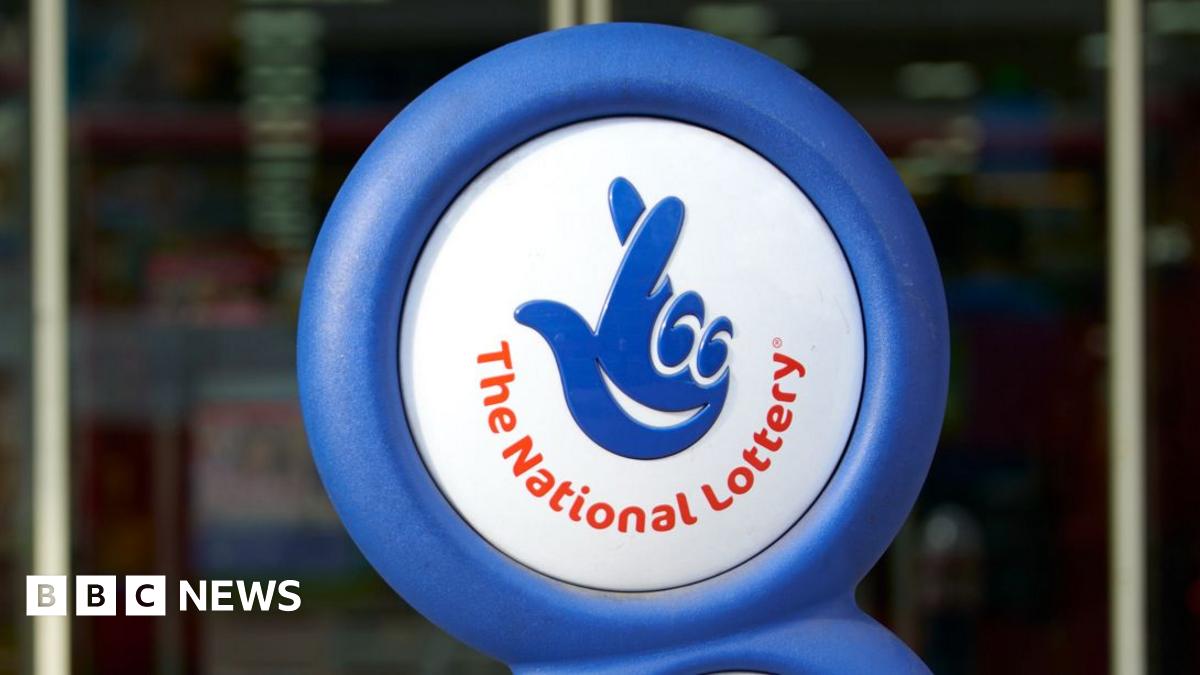 A photograph of the National Lottery logo displayed outside a shop