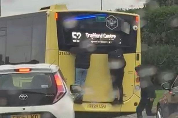 Two teenagers clinging onto the back of a bus near the Trafford Centre, in Manchester. // Shocking video footage shows two teenagers clinging onto the back of a bus on a busy main road. The horror footage - which was filmed on a shocked member of the public's phone - captures the two boys hanging off the back of a Bee Network bus near the Trafford Centre, in Manchester, yesterday (Oct 19). The teenagers - both dressed in black coats - had climbed onto the back of a 52 service which travels from Failsworth to Trafford. The 12 clip was filmed at the Ellesmere Circle roundabout as the bus made its way down Redclyffe Road.