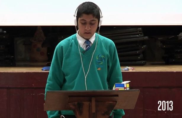 a school boy in a green uniform reading at a podium