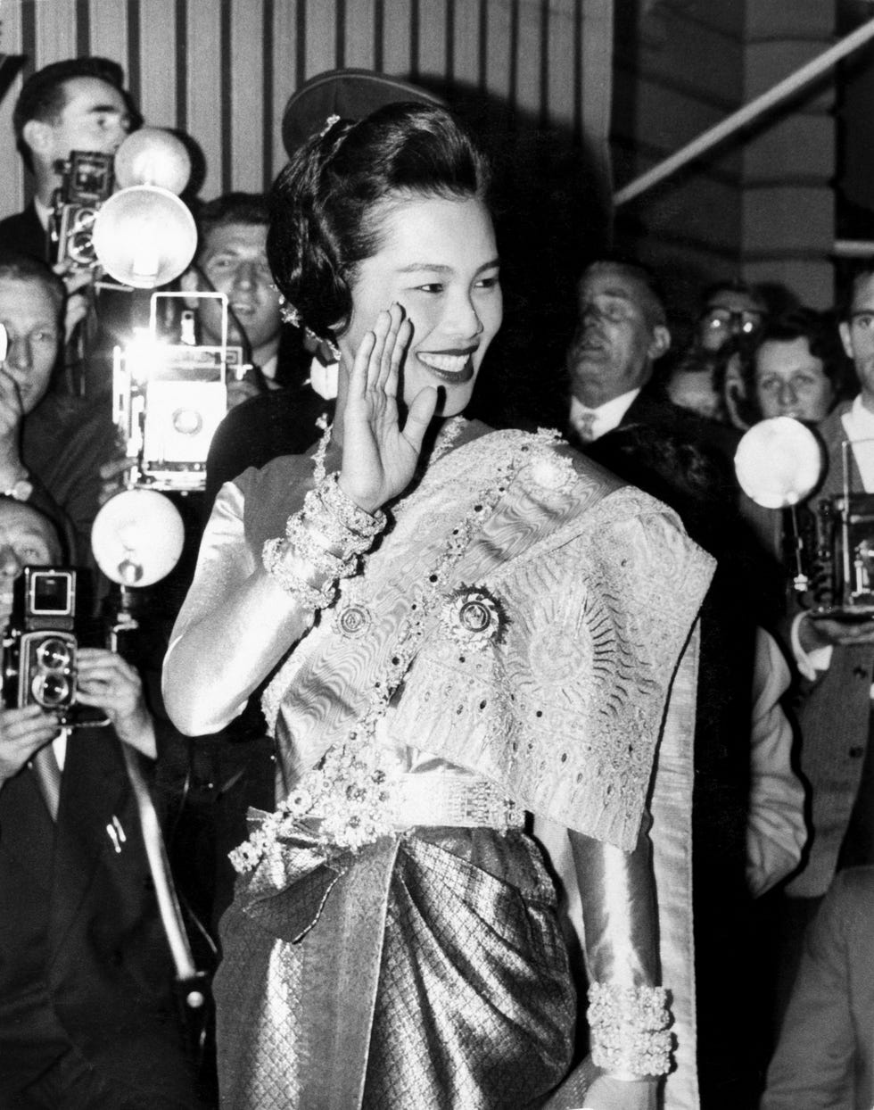 Woman dressed in formal attire greeting a crowd of photographers