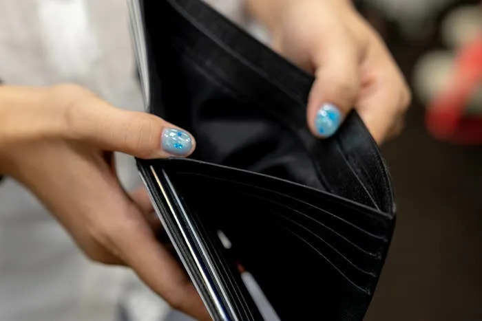 Person holding an open, empty wallet with patterned fingernails visible