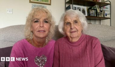 Judith Bosustow sitting on the left with blond hair in a pink jumper, beside her mum, Joan, in a purple jumper with white hair