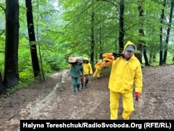 Ukrainian researchers carry equipment to a suspected mass grave in the Carpathian mountains of southeast Poland on September 30.