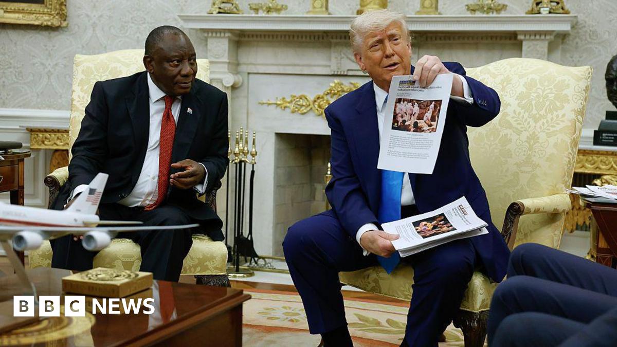 President Trump holding up papers with images during next to President Ramaphosa.