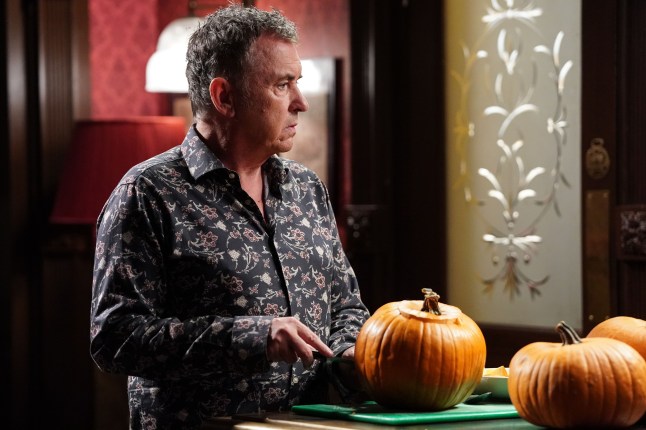 Alfie stands by some pumpkins in the pub looking worried in EastEnders