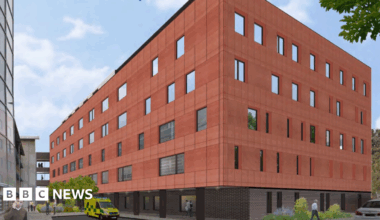 An artist's impression of a new six-storey building on a hospital site. There is an ambulance outside and a man on a mobile phone.