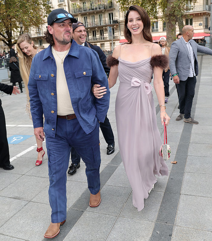 Lana Del Rey and husband walking outdoors, with husband praised for being classier after Meghan Markle backlash. Lana Del Rey and husband walking outdoors, with husband praised for being classier after Meghan Markle backlash.