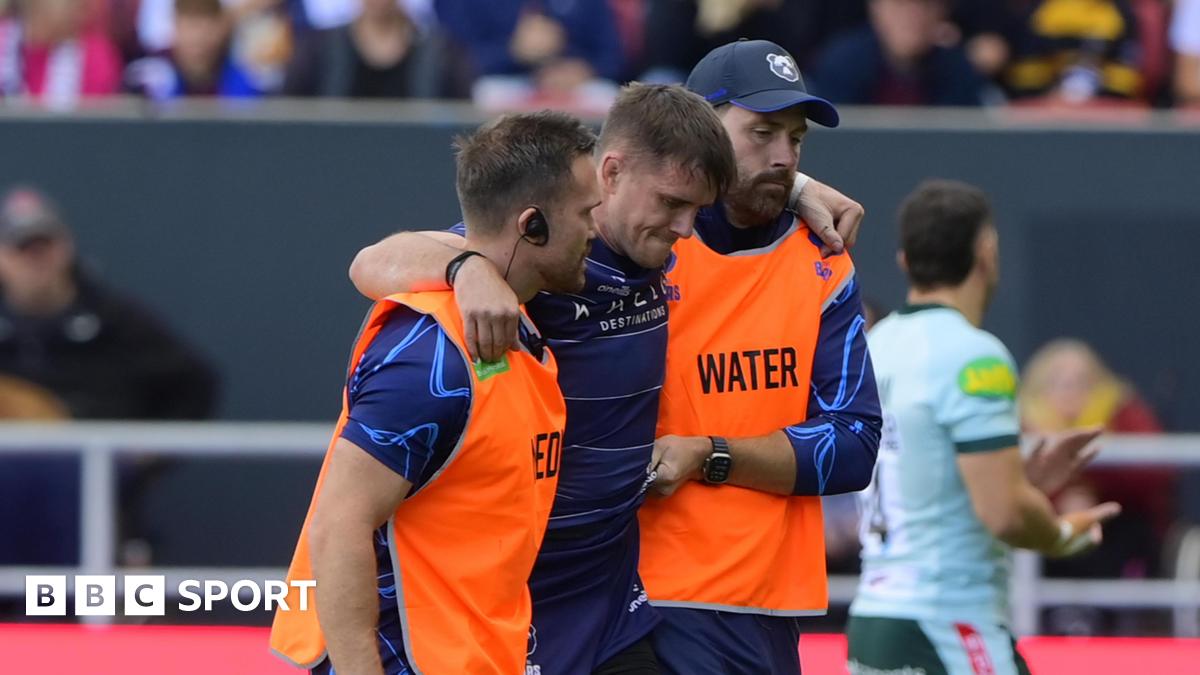 AJ MacGinty being helped off the pitch by two Bristol staff members