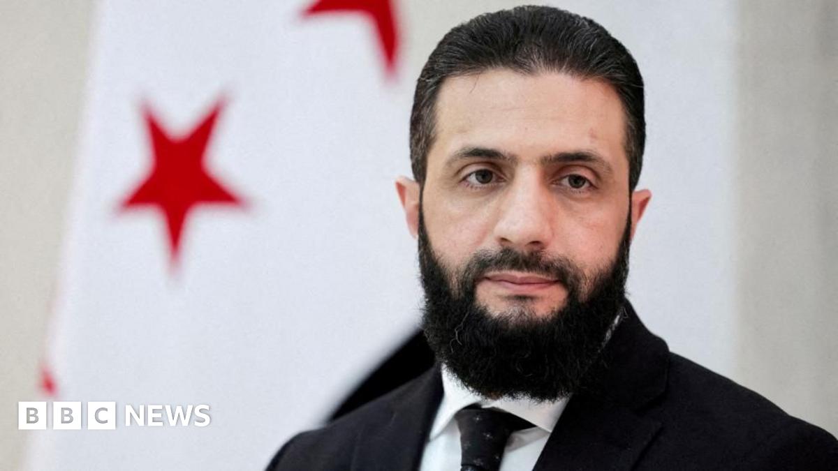 Syrian President Ahmed al-Sharaa waves amid a crowd of people