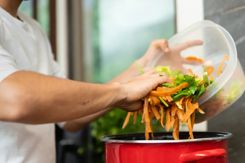 Person adding sliced vegetables into a pot, preparing a meal