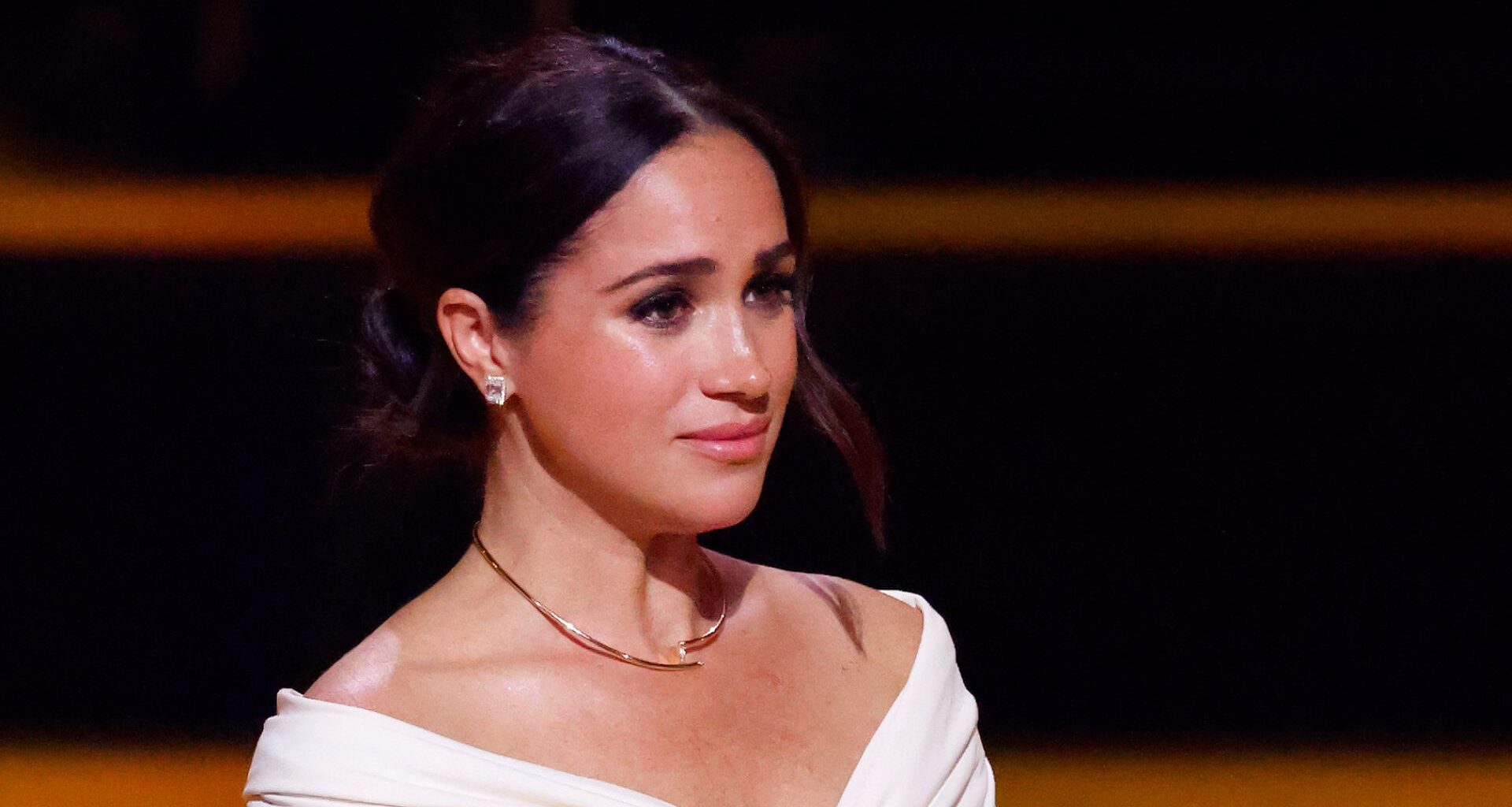 Meghan Markle looks tearful at an event while wearing a white top