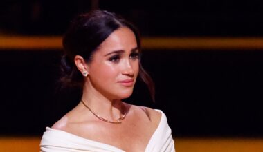 Meghan Markle looks tearful at an event while wearing a white top