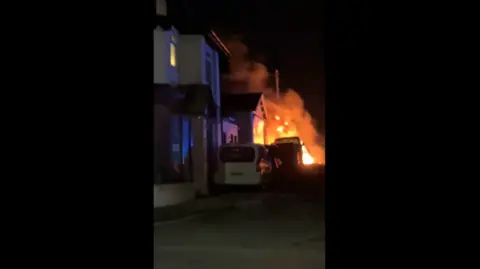 Eddie Mitchell A screenshot of a video showing a building on fire. 