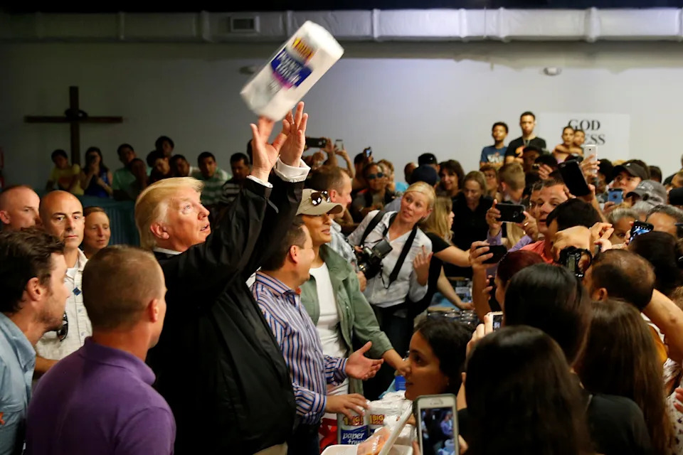 U.S. President Donald Trump tosses rolls of paper towels to people at a hurricane relief distribution center at Calvary Chapel in San Juan, Puerto Rico, October 3, 2017. \