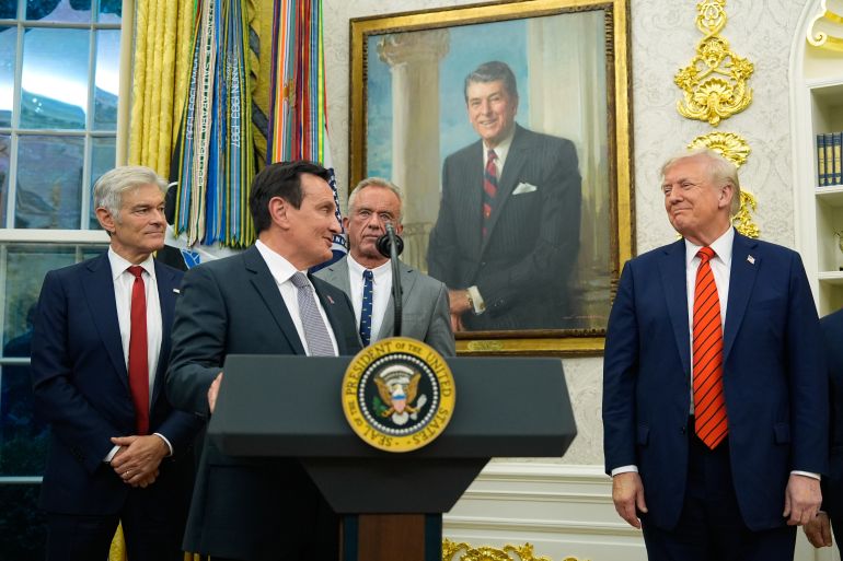 Pascal Soriot speaks behind a presidential podium in the Oval Office, standing next to Trump.