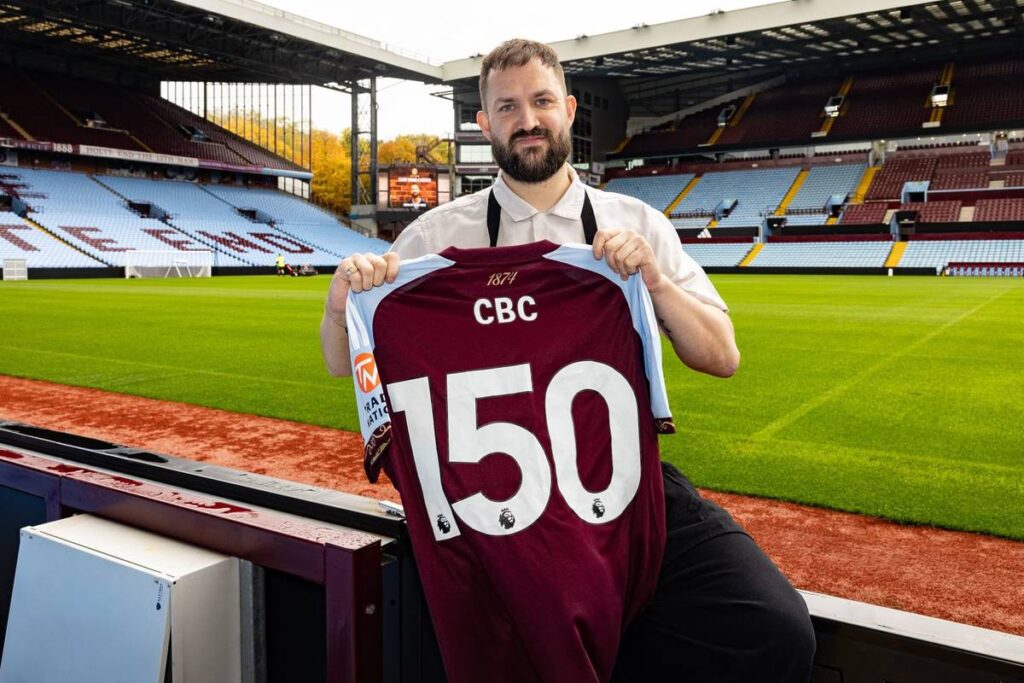 Brad Carter holding up a Villa shirt