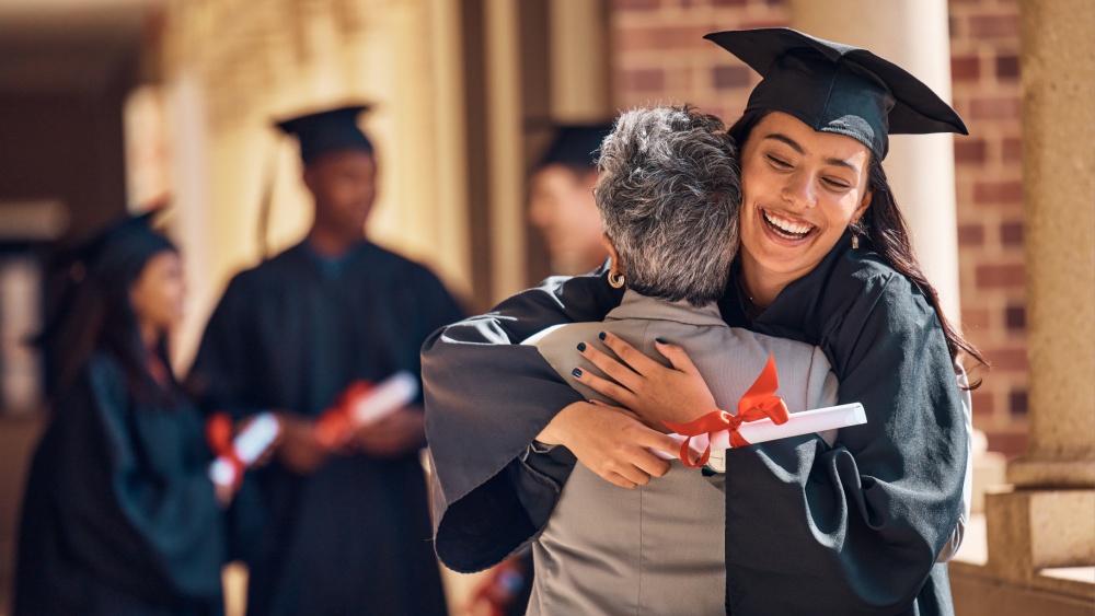 graduating girl looking happy hugging another woman