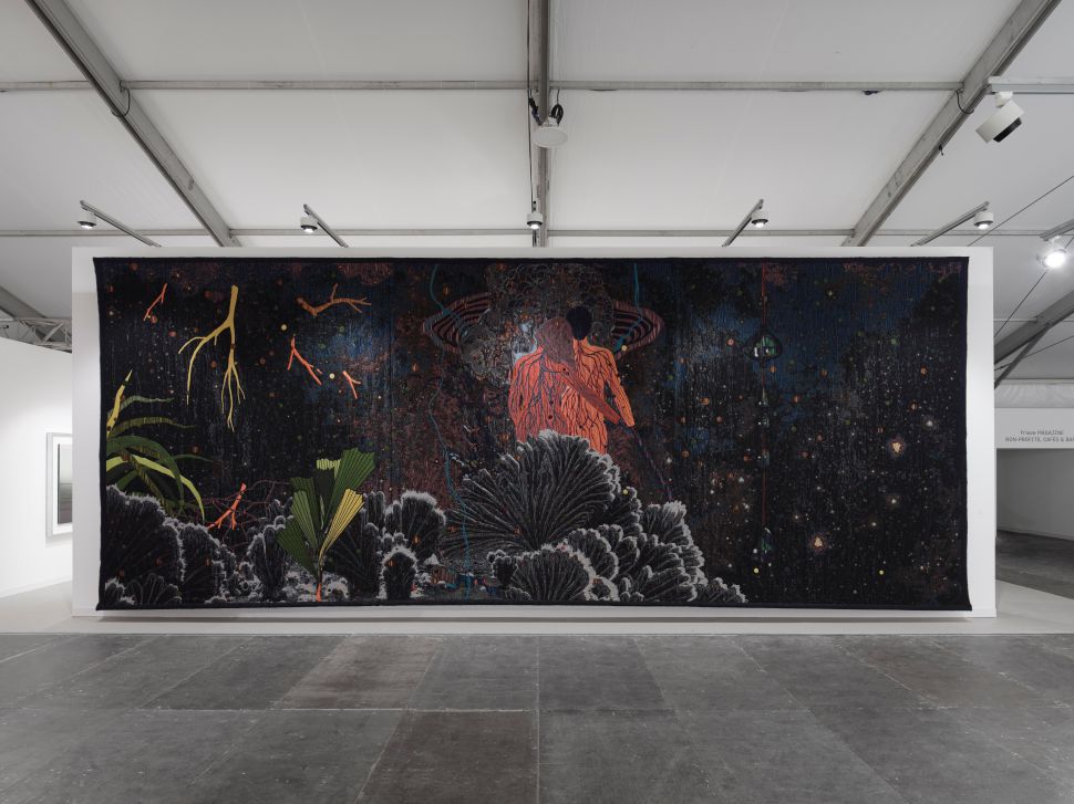 Massive dark tapestry depicting cosmic and botanical elements with two orange figures in the center, spanning an entire wall of the booth.