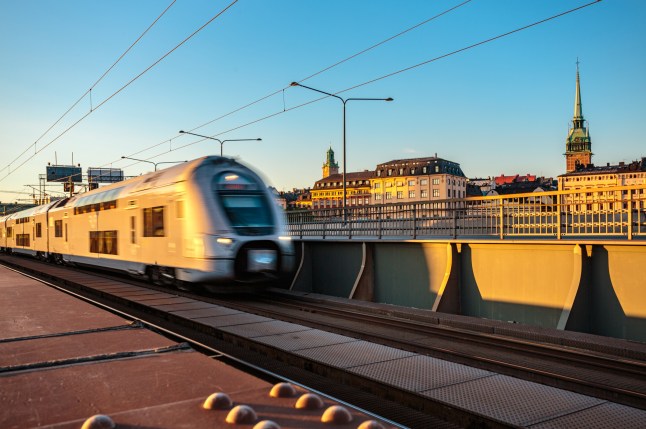 A train passing buildings and a church on a bridge in Stockholm. Sweden.