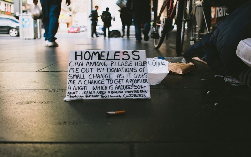 A sign on a street by a homeless person asking for donations of small change