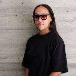 A woman wearing a black T-shirt and sunglasses.