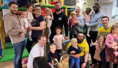 A group of Dads with their young children in front of soft play equipment