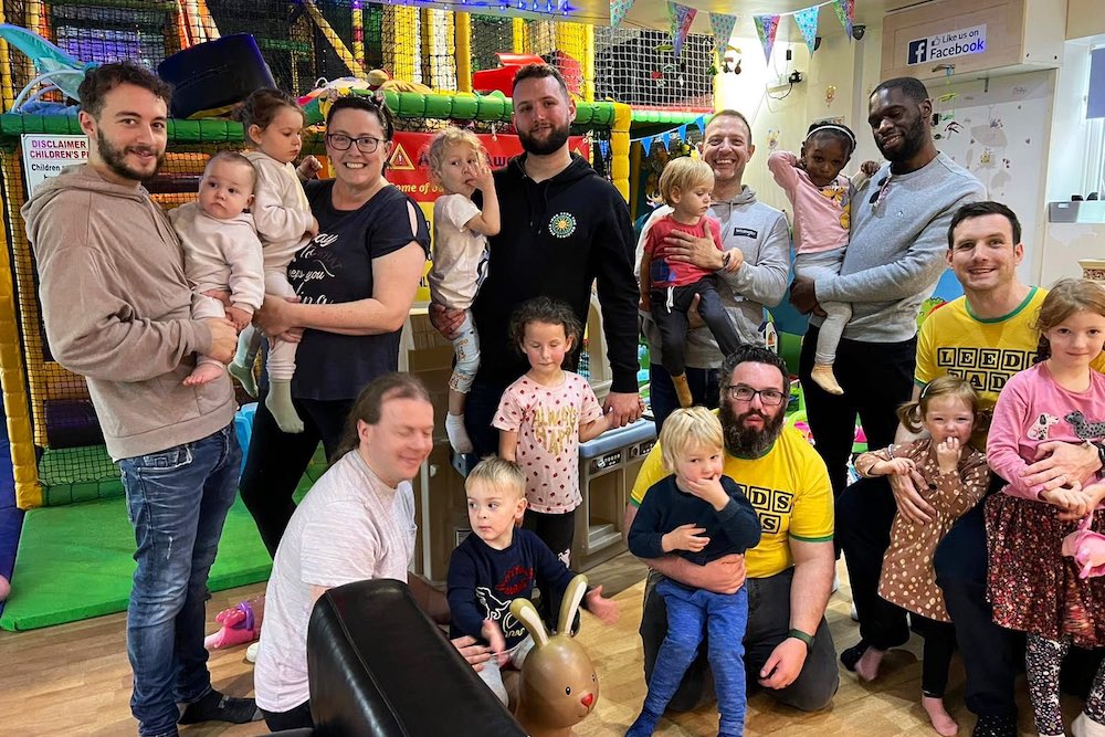 A group of Dads with their young children in front of soft play equipment