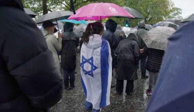 A woman wears the flag of Israel wrapped over her back as she attends a vigil for the victims of the attack on at Heaton Park Hebrew Congregation synagogue, in Crumpsall, Manchester, England, Friday, Oct. 3, 2025. (AP Photo/Ian Hodgson)
