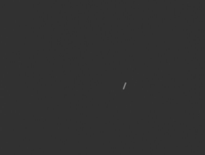 A dark, almost black background with a single thin, short, white diagonal line slightly off-center.
