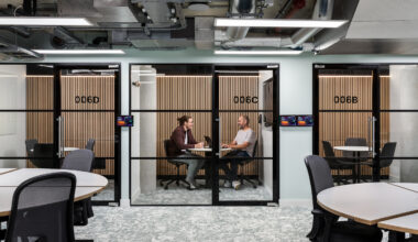 Two people sit across from each other at a small table inside a glass-walled meeting room at Northeastern University’s London startup hub, which houses 22 external businesses and provides students with hands-on work opportunities.