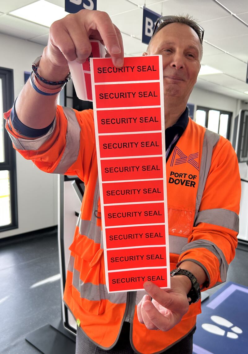 A Port of Dover official holds up the new security seal stickers for coaches