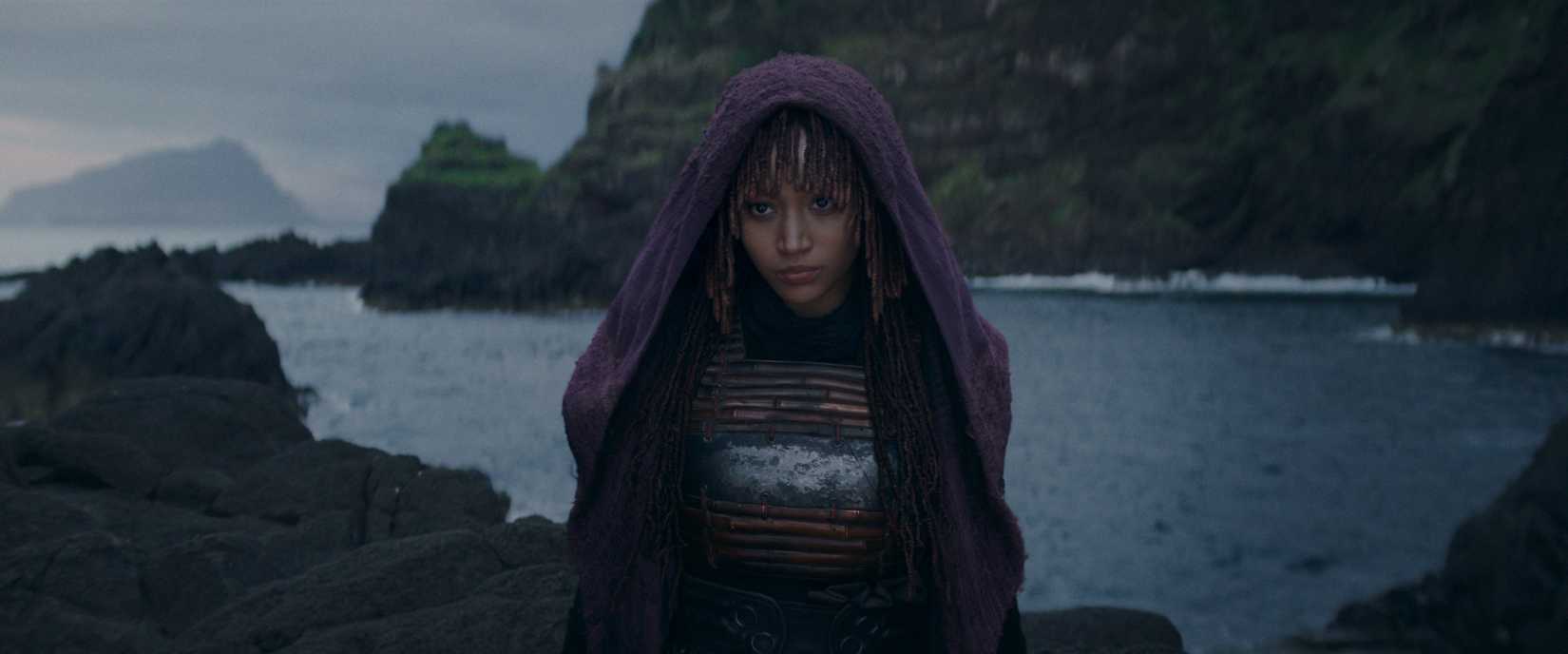 Amandla Stenberg looking vaguely evil over a cliff face in front of water in The Acolyte