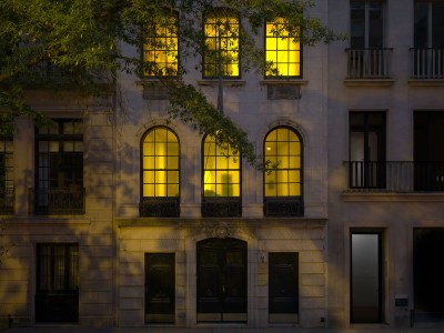 A townhouse with its windows lit yellow from inside.