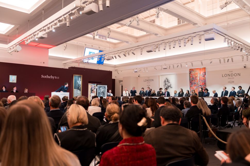 Wide view of a packed Sotheby’s evening sale room with specialists seated along the rostrum and multiple artworks, including a Bacon, displayed on the walls.