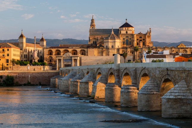 An arched bridge over a river in Cordoba, Spain, with buildings on the other side.