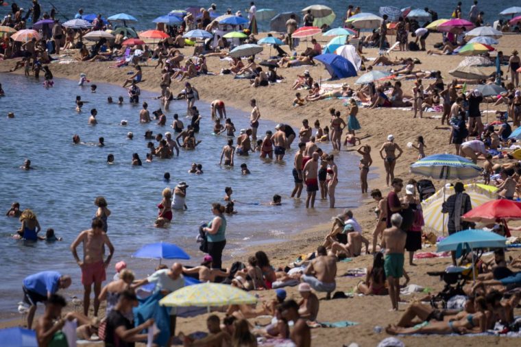 FILE - Bathers cool off in the water while others sunbathe on a Barcelona beach, Spain, Wednesday, July 24, 2024. (AP Photo/Emilio Morenatti,File)