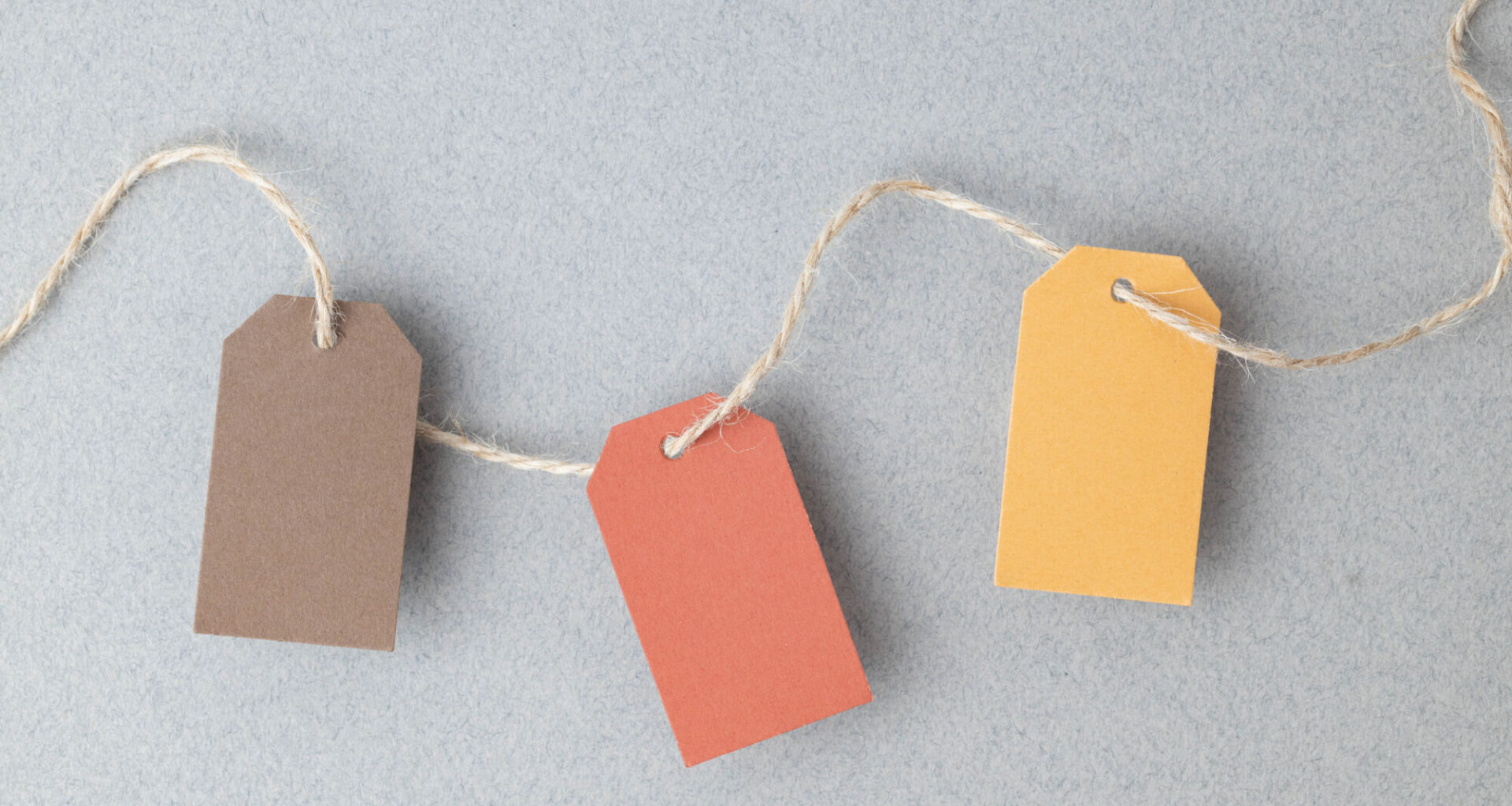 Autumn color palette, blank gift tags with jute twine string on a gray textured surface with copy space.