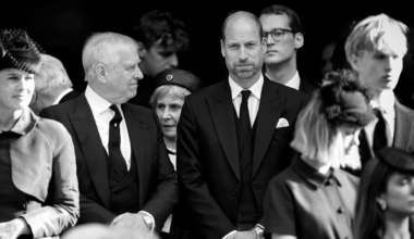 Prince William, wearing a black suit at Duchess of Kent's funeral, looking serious as Prince Andrew turns to smile at him