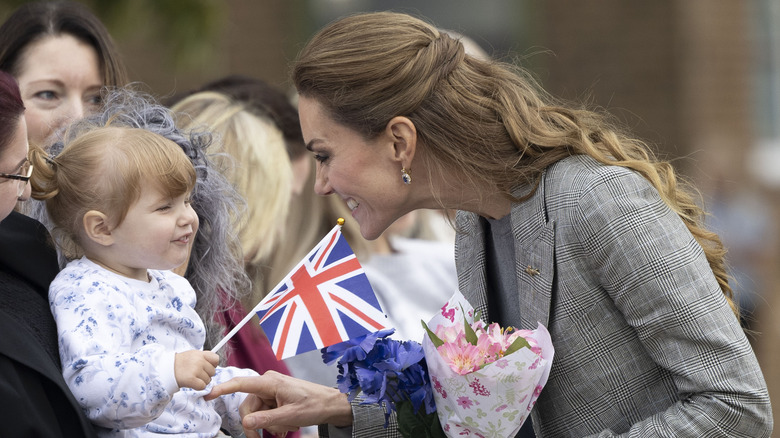 Princess Catherine smiling and talking with toddler in crowd